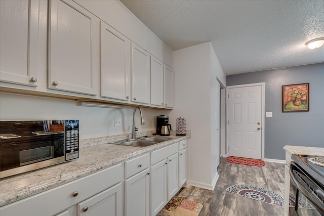 2382 Patrick Ave, Hephzibah, GA 30815 - kitchen with a sink, appliances with stainless steel finishes, a textured ceiling, light wood finished floors, and white cabinetry