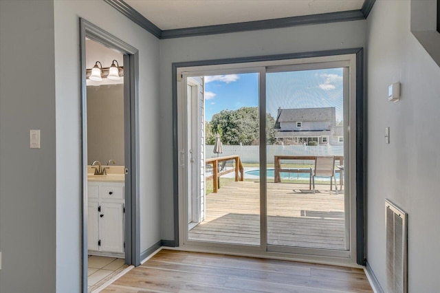 entryway featuring visible vents, light wood-style flooring, baseboards, and ornamental molding