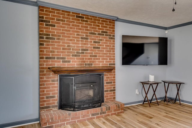 details with wood finished floors, baseboards, a fireplace, a textured ceiling, and crown molding