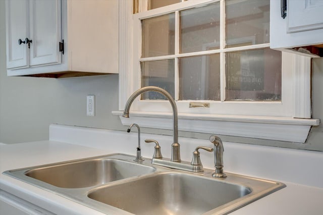 room details with a sink, white cabinetry, and light countertops
