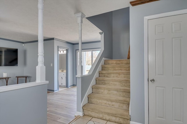 stairs featuring baseboards, a textured ceiling, wood finished floors, and crown molding