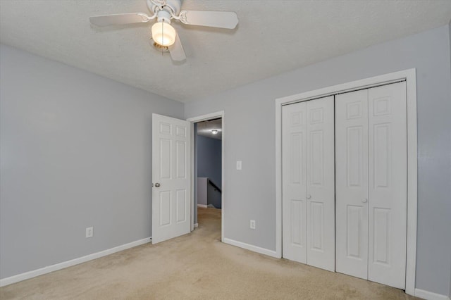 unfurnished bedroom featuring carpet, baseboards, ceiling fan, a closet, and a textured ceiling