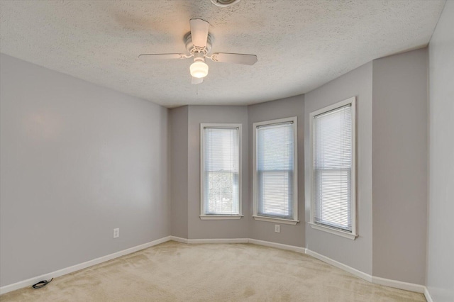 carpeted empty room with baseboards, a textured ceiling, and a ceiling fan