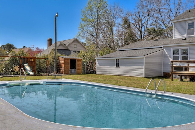 view of swimming pool featuring an outbuilding, a playground, a yard, and a fenced in pool