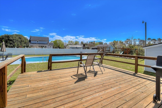 wooden deck with a playground, a lawn, a fenced in pool, and a fenced backyard