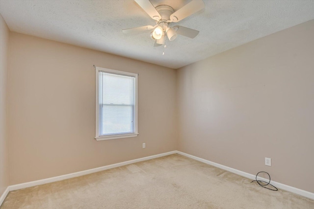 unfurnished room with ceiling fan, light colored carpet, baseboards, and a textured ceiling