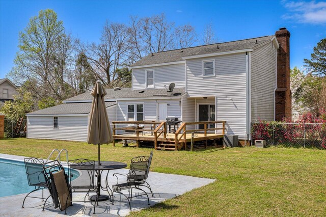 back of property with fence, a chimney, a deck, a patio area, and a lawn