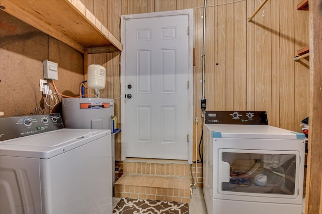 clothes washing area with separate washer and dryer and wood walls