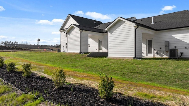 rear view of property featuring a lawn and central air condition unit