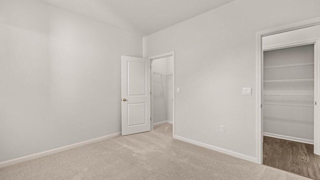 unfurnished bedroom with light carpet, a walk in closet, and a closet