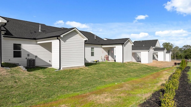 rear view of house featuring central AC unit and a lawn