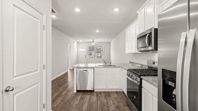 kitchen featuring light stone counters, stainless steel appliances, dark hardwood / wood-style flooring, a kitchen breakfast bar, and sink