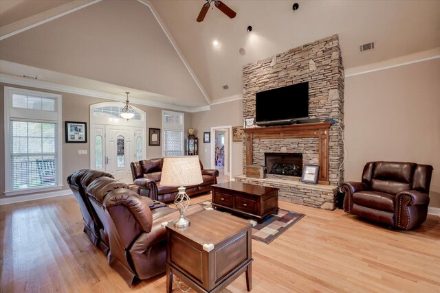 living room featuring ceiling fan, a stone fireplace, light wood-type flooring, and high vaulted ceiling