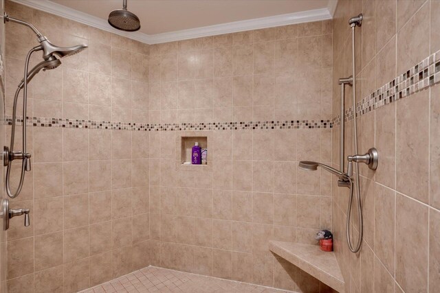 bathroom with ornamental molding and tiled shower