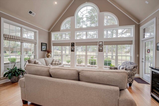 living room with light hardwood / wood-style flooring, high vaulted ceiling, and ornamental molding