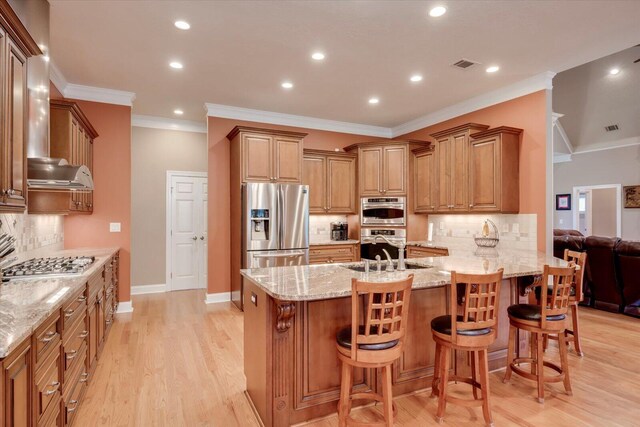 kitchen featuring a breakfast bar area, decorative backsplash, light stone countertops, and stainless steel appliances