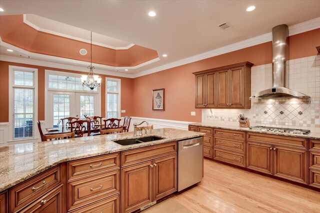 kitchen featuring sink, ornamental molding, wall chimney range hood, and appliances with stainless steel finishes