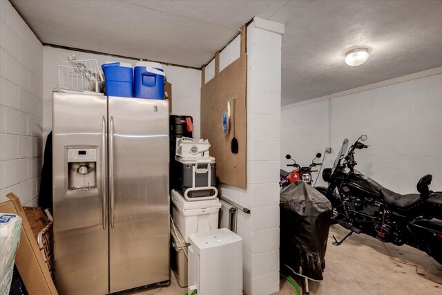 interior space featuring a textured ceiling and stainless steel refrigerator with ice dispenser