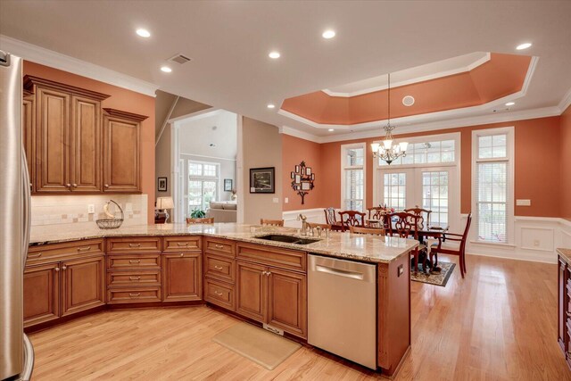 kitchen with kitchen peninsula, appliances with stainless steel finishes, a raised ceiling, and sink