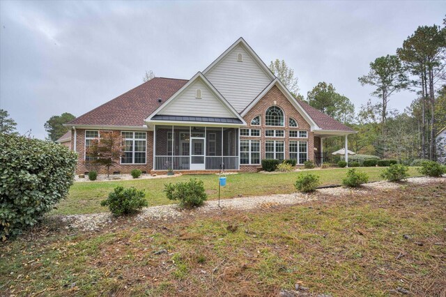 back of property with a yard and a sunroom