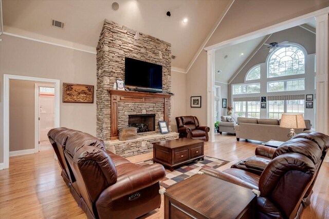 living room with high vaulted ceiling, light hardwood / wood-style flooring, ceiling fan, and a stone fireplace