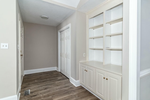 interior space with baseboards, visible vents, dark wood finished floors, and a textured ceiling