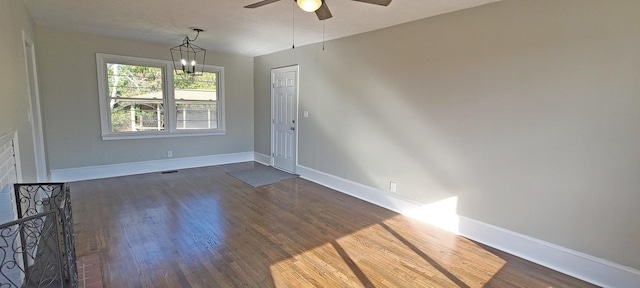 spare room featuring ceiling fan with notable chandelier and dark hardwood / wood-style flooring