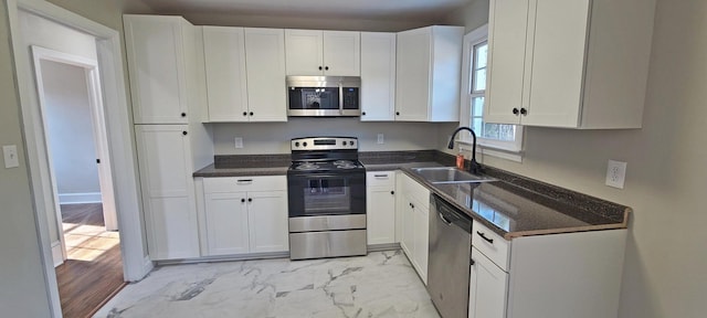 kitchen featuring stainless steel appliances, white cabinetry, and sink