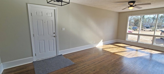 foyer entrance with dark wood-type flooring, a textured ceiling, and ceiling fan