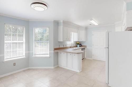 kitchen featuring white cabinets, white fridge, sink, and crown molding