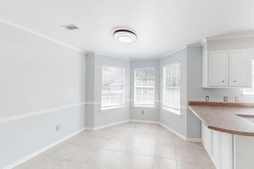 unfurnished dining area with ornamental molding and light tile patterned floors