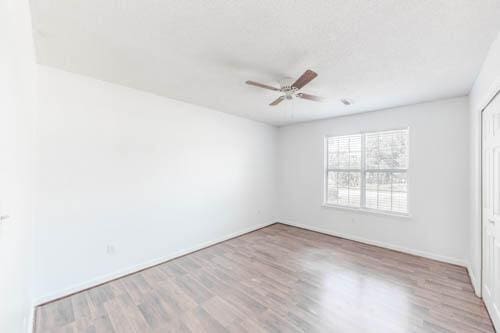 empty room with ceiling fan and light hardwood / wood-style flooring