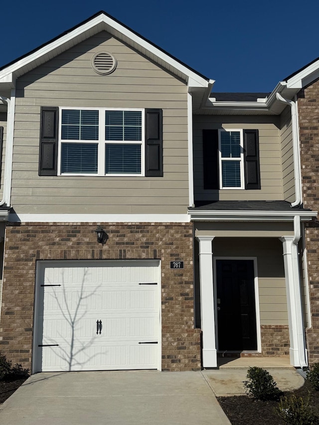 view of front of property featuring concrete driveway, an attached garage, and brick siding