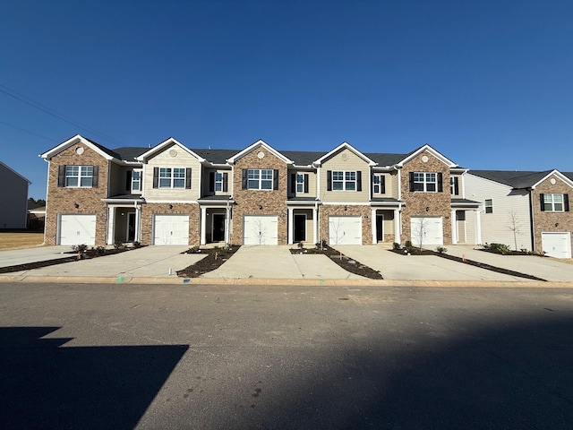 view of property featuring an attached garage, brick siding, and driveway