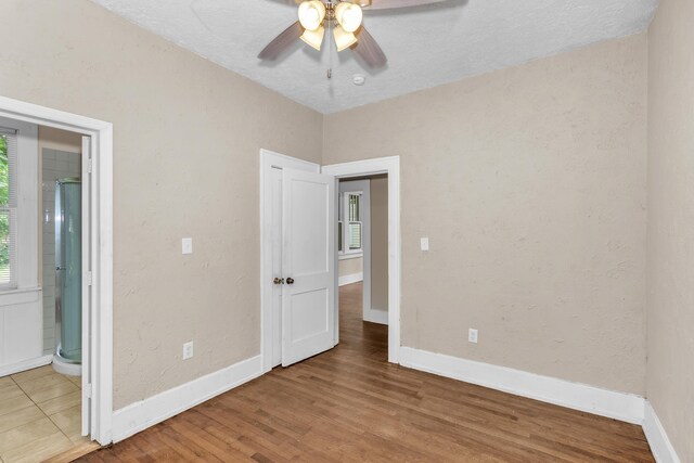 unfurnished bedroom featuring ensuite bath, ceiling fan, and hardwood / wood-style floors