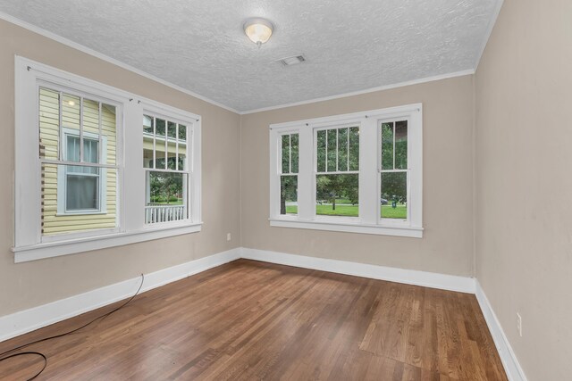 spare room with a textured ceiling, hardwood / wood-style flooring, and plenty of natural light