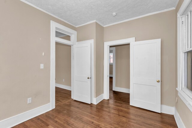 unfurnished bedroom with a textured ceiling, ornamental molding, and dark wood-type flooring