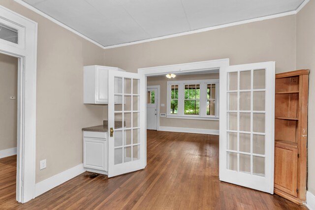 unfurnished dining area featuring french doors, dark hardwood / wood-style flooring, and ornamental molding