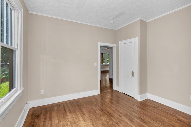 spare room with hardwood / wood-style flooring, ornamental molding, a textured ceiling, and a wealth of natural light