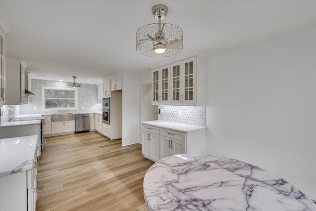 kitchen featuring stainless steel appliances, decorative light fixtures, light hardwood / wood-style flooring, and white cabinets