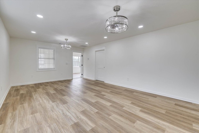 unfurnished room with a chandelier, recessed lighting, light wood-style flooring, and baseboards