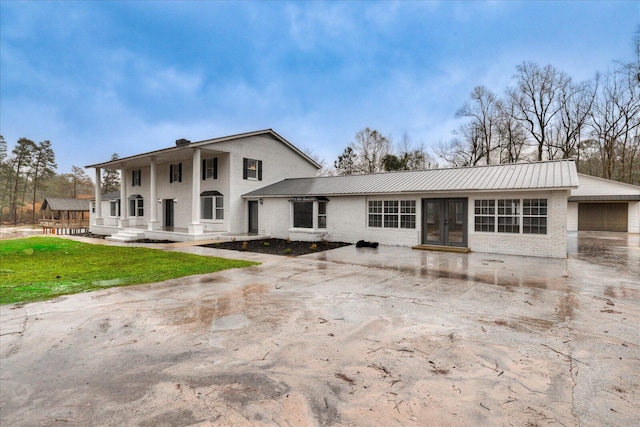 view of front of home featuring brick siding, metal roof, and a front yard