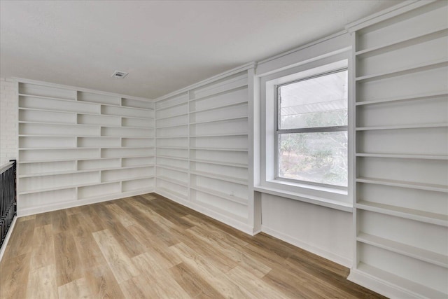 unfurnished room featuring built in features, light wood-type flooring, and visible vents