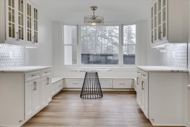 kitchen featuring ceiling fan, white cabinetry, decorative backsplash, decorative light fixtures, and light wood-type flooring