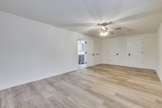 unfurnished room featuring light wood finished floors, a textured ceiling, baseboards, and a ceiling fan