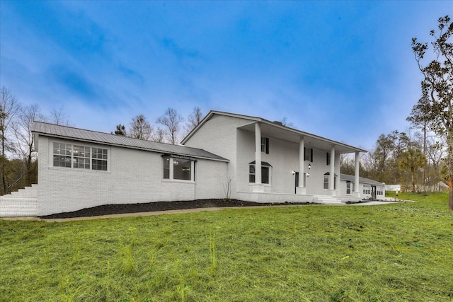 exterior space with metal roof, a front lawn, and brick siding