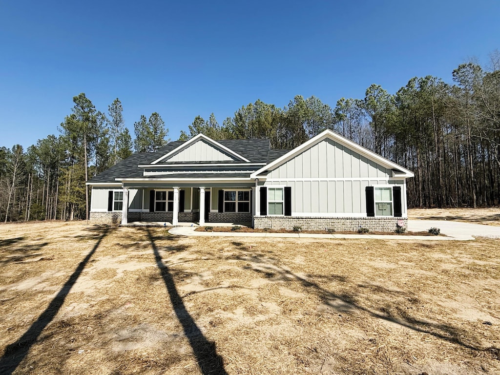 view of front facade with brick siding, board and batten siding, and a porch