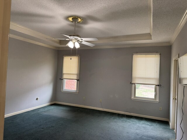 empty room with dark carpet, ornamental molding, a textured ceiling, and a tray ceiling