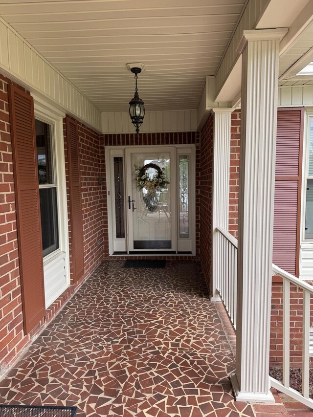 property entrance with covered porch and brick siding
