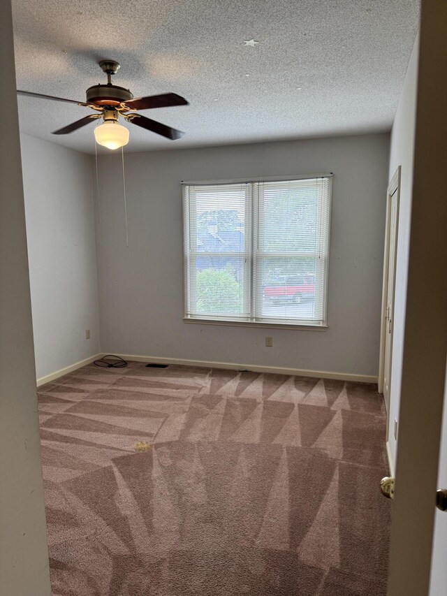 unfurnished room featuring baseboards, ceiling fan, carpet, and a textured ceiling